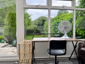 a desk in front of a window with a fan at 2 Bedroom House in Bloxwich