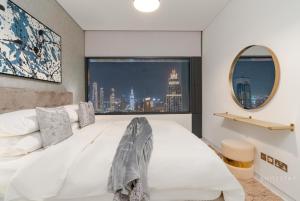 a bedroom with a large white bed and a window at Skyline Burj Facing Suite in Dubai