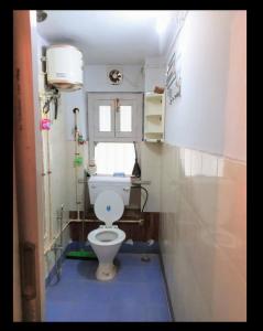 a bathroom with a toilet and a window at Happy Home in Kolkata