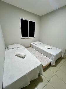 2 camas en una habitación blanca con ventana en Apartamento - 3 Quartos climatizados - By BellaEstadia, en Aracaju