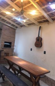 - une table en bois dans une chambre avec une guitare sur le mur dans l'établissement Casa temporada com Piscina, à Governador Celso Ramos