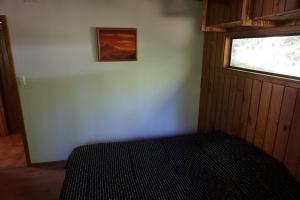 1 dormitorio con 1 cama en una habitación con ventana en Cabaña compartida en santuario de la naturaleza Rio Cutipay, en Valdivia