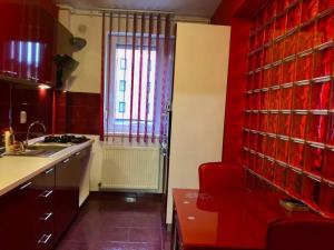 eine rote Küche mit einer Spüle und einem roten Stuhl in der Unterkunft Joy City Stay Martirilor Giroc 4 in Timişoara