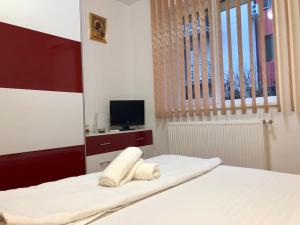 Schlafzimmer mit einem Bett mit weißer Bettwäsche und einem TV in der Unterkunft Joy City Stay Martirilor Giroc 4 in Timişoara