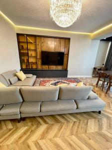 um grande sofá numa sala de estar com um lustre em Designer apartment near the Gum shopping center em Bishkek