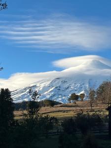 una montaña cubierta de nieve con una nube sobre ella en Casa Condominio Pucon Villarrica, en Molco
