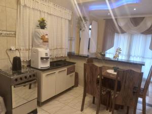 una cucina con piano cottura e tavolo con forno a microonde di Casa temporada com Piscina a Governador Celso Ramos