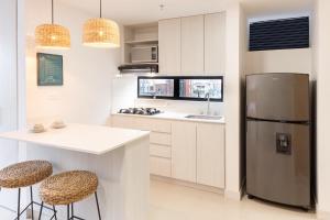 a kitchen with a refrigerator and a counter with stools at Origen Local Suites in Medellín