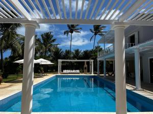 una piscina con una pérgola blanca y una casa en Maracajau Luxury Home - Villa-Mar-a-Villa en Maxaranguape