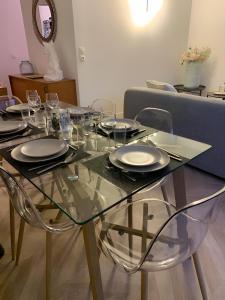a glass table with plates and glasses on it at Magnifique Appartement, 3 min de Paris in Levallois-Perret