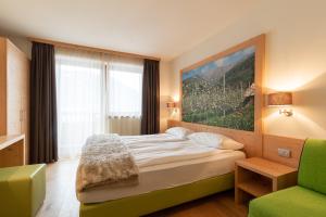 een slaapkamer met een groot bed en een groene stoel bij Agritur Il Tempo delle Mele in Caldes