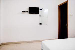 Flagship Hotel Lotus Inn في فاراناسي: غرفة بسريرين وتلفزيون على الحائط