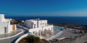 a white building with the ocean in the background at Terra Blanca Suites in Imerovigli