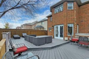 un patio con parrilla y sillas en una terraza de madera en 5 amazing bedrooms in suburban delight!, en Pickering
