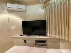 TV de pantalla plana en un armario en una habitación en アルカディア en Maizuru