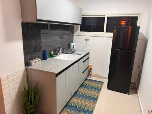 eine Küche mit einer Spüle und einem schwarzen Kühlschrank in der Unterkunft Duke of the Dead Sea by CROWN in Neve Zohar