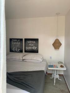 a bed in a room with two pictures on the wall at Almas Gêmeas suíte in Angra dos Reis