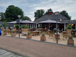 een restaurant met tafels, stoelen en parasols bij De Tip 31 Tiny Chalet in Zeeland