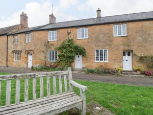 a wooden bench in front of a brick building at Two Towers Cottage in Montacute