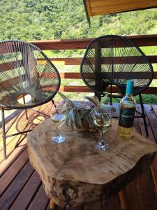 een tafel met twee stoelen en wijnglazen op een terras bij Chalé Sítio São José in Santo Antônio do Pinhal