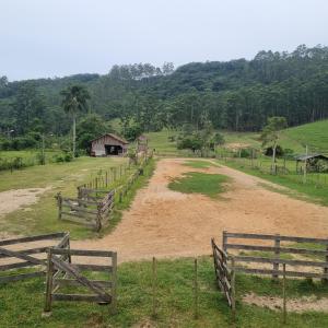 a dirt road in a field with wooden fences at Casa no Sítio in Penha