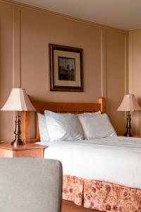 a bedroom with a large white bed with two lamps at Auberge Des 3 Canards in La Malbaie