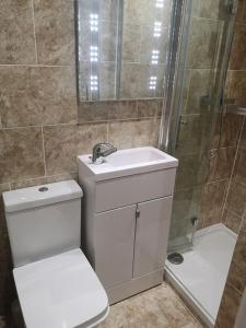 La salle de bains est pourvue de toilettes, d'un lavabo et d'une douche. dans l'établissement NightRest Homes 5 Bedroom House - Smart Tv in Each Room-Parking-Wifi, à Welwyn Garden City