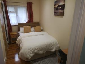 sypialnia z łóżkiem z białą pościelą i oknem w obiekcie NightRest Homes 5 Bedroom House - Smart Tv in Each Room-Parking-Wifi w mieście Welwyn Garden City