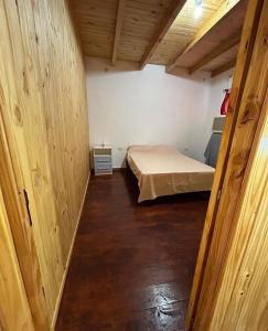a small bedroom with a bed in a room with wooden walls at Gobernador Roca Duplex in Gobernador Roca
