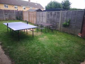 a ping pong table and chairs in a yard at NightRest Homes 5 Bedroom House - Smart Tv in Each Room-Parking-Wifi in Welwyn Garden City
