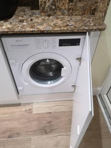una lavadora en una cocina bajo una encimera en NightRest Homes 5 Bedroom House - Smart Tv in Each Room-Parking-Wifi en Welwyn Garden City
