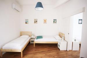 two beds in a room with white walls and wooden floors at Jókai 19 Vendégház in Veszprém