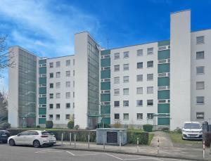 un edificio blanco con coches estacionados en un estacionamiento en 3 Zimmer Familienwohnung mit WLAN & Netflix en Mönchengladbach