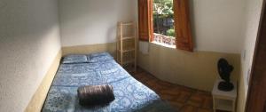 a bedroom with a bed with a blue comforter and a window at Hostel do Coreto in Mucugê