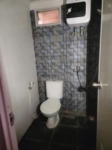 baño con aseo y pared de azulejos en Metro Suits Apartment Bandung en Bandung