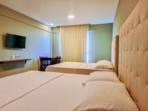 a hotel room with two beds and a flat screen tv at Ilusion Flat Ponta Negra in Natal