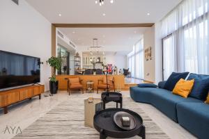 ein Wohnzimmer mit einem blauen Sofa und einem TV in der Unterkunft AYA Boutique - Oasis in Al Muntazah 3BR Villa with Private Pool in Abu Dhabi