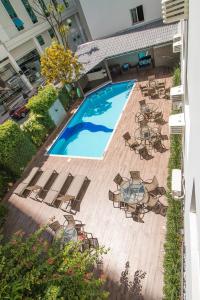 - une vue sur la piscine dotée de tables et de chaises dans l'établissement Hotel Gracher Praia, à Balneário Camboriú