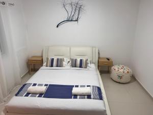 a bedroom with a white bed with blue and white pillows at Duchess of the Dead Sea by CROWN in Neve Zohar