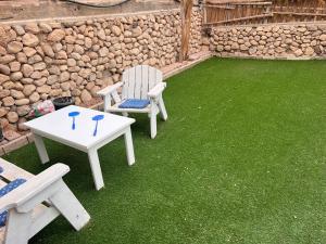 a patio with two chairs and a table and grass at Duchess of the Dead Sea by CROWN in Neve Zohar