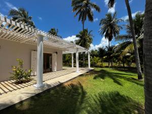 a house with a white pergola and palm trees at Maracajau Luxury Home - Villa-Mar-a-Villa in Maxaranguape
