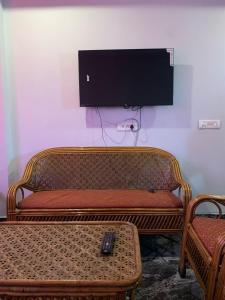 a tv on a wall with a couch and a remote control at Modern Comforts with a view in Dehradun