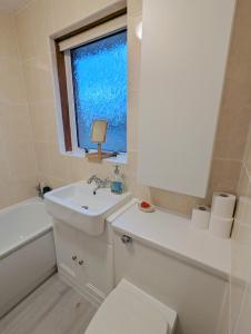 een badkamer met een wastafel, een toilet en een raam bij Single room with Castle view in Edinburgh
