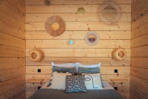 a bedroom with a wooden wall with a bed at LES CABANES DE LUTINA 
