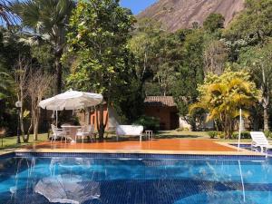 una piscina con sillas y sombrilla en Casa na Serra incrivel com vista para as montanhas, en Petrópolis