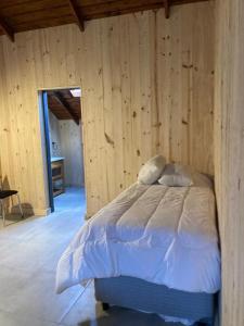 a bedroom with a bed in a wooden wall at Galpon de Burgos - SalePatagonia in San Martín de los Andes
