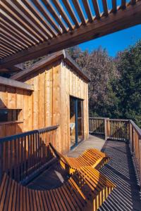 a wooden cabin with a wooden deck with a bench at LES CABANES DE LUTINA 