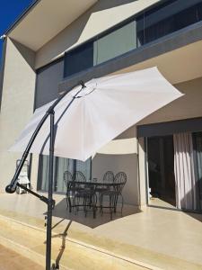- un parasol blanc sur une terrasse avec des chaises et une table dans l'établissement Villa Deluxe Au Pied de l'Atlas, à Ksar et Tlatia
