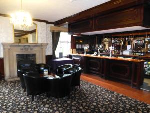a bar with black chairs and a table and a fireplace at Maes Manor Country Hotel in Blackwood