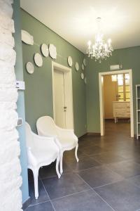 a dining room with white chairs and a chandelier at Terrazzani Suite in Comiso